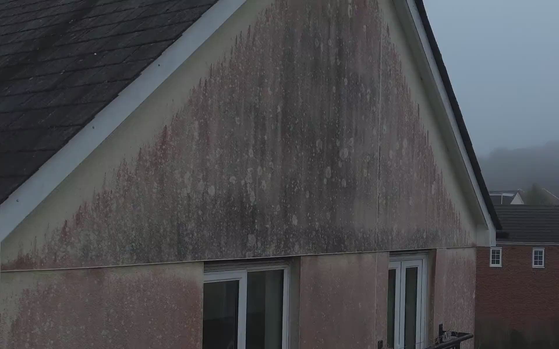 Drone view of a rendered gable streaked with red algae, before our crew washes it clean
