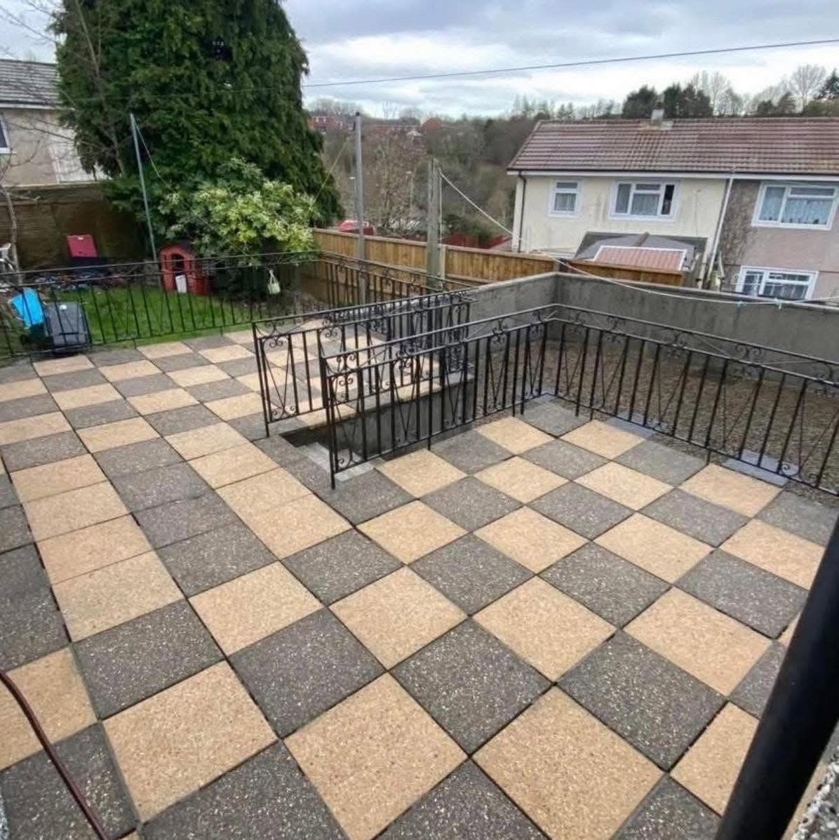 Checkerboard patio and steps after pressure washing, the buff and charcoal slabs back to their own colours