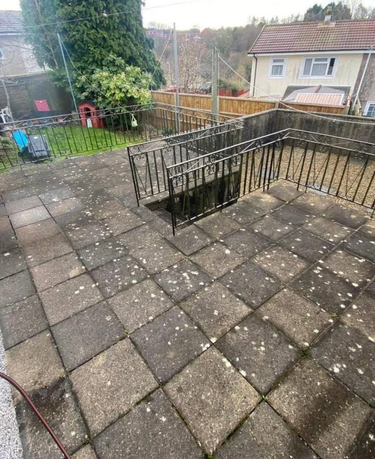 Checkerboard patio and steps furred with moss and black spots, before cleaning